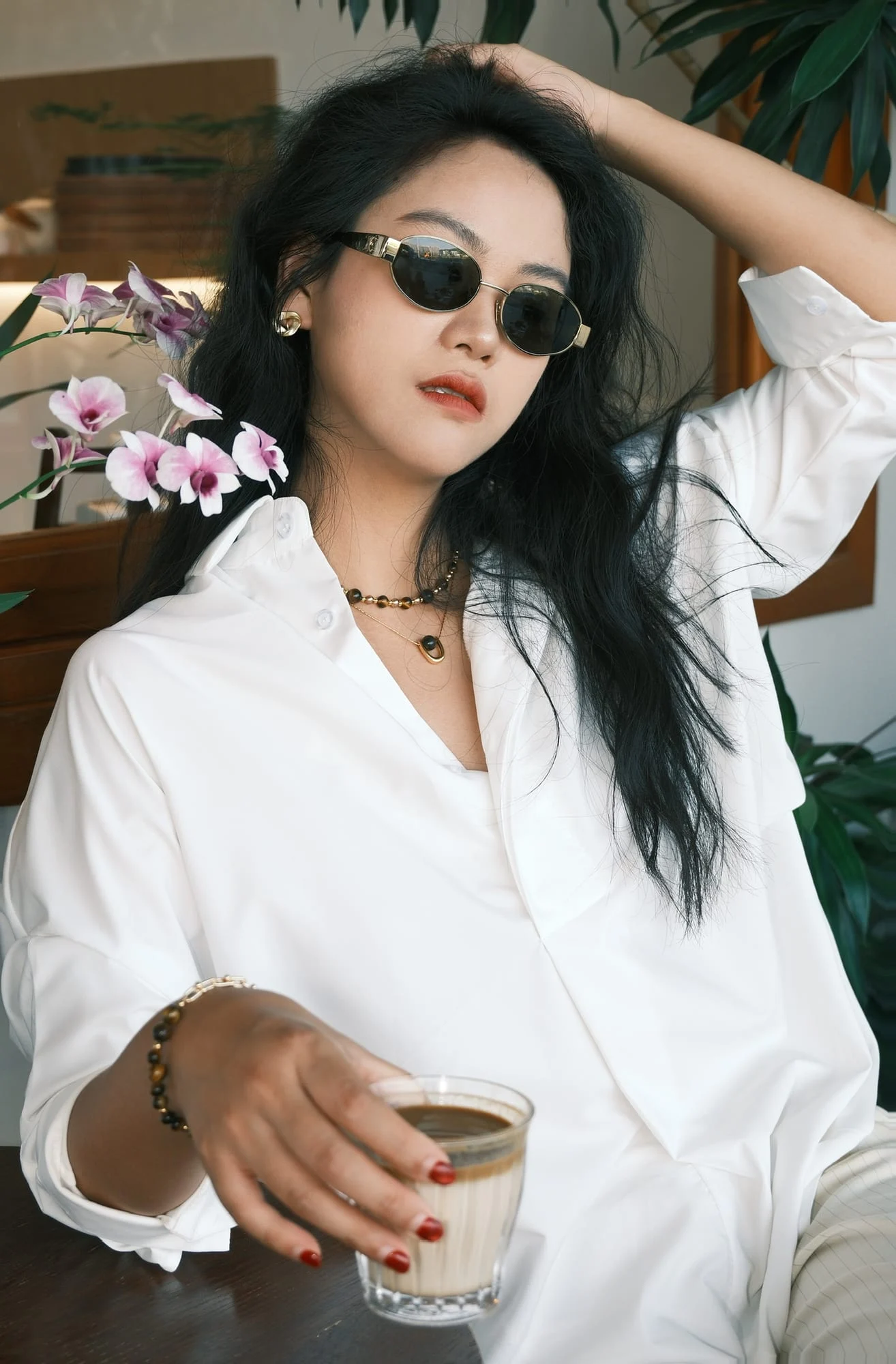 The gold-toned folded stud worn by a model in a white shirt and gold-toned sunglasses.
